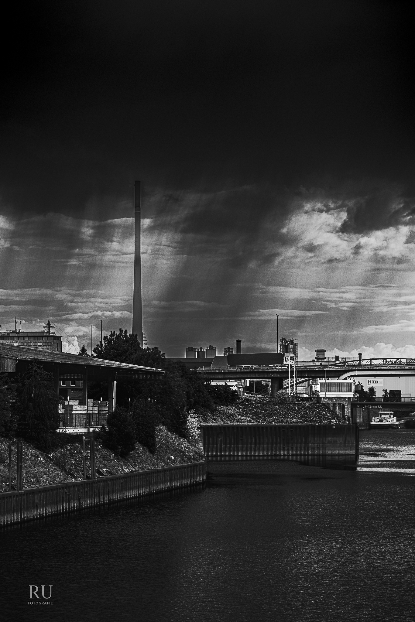 Wasserfläche und Brücke im Duisburger Innenhafen unter dunklen Wolken